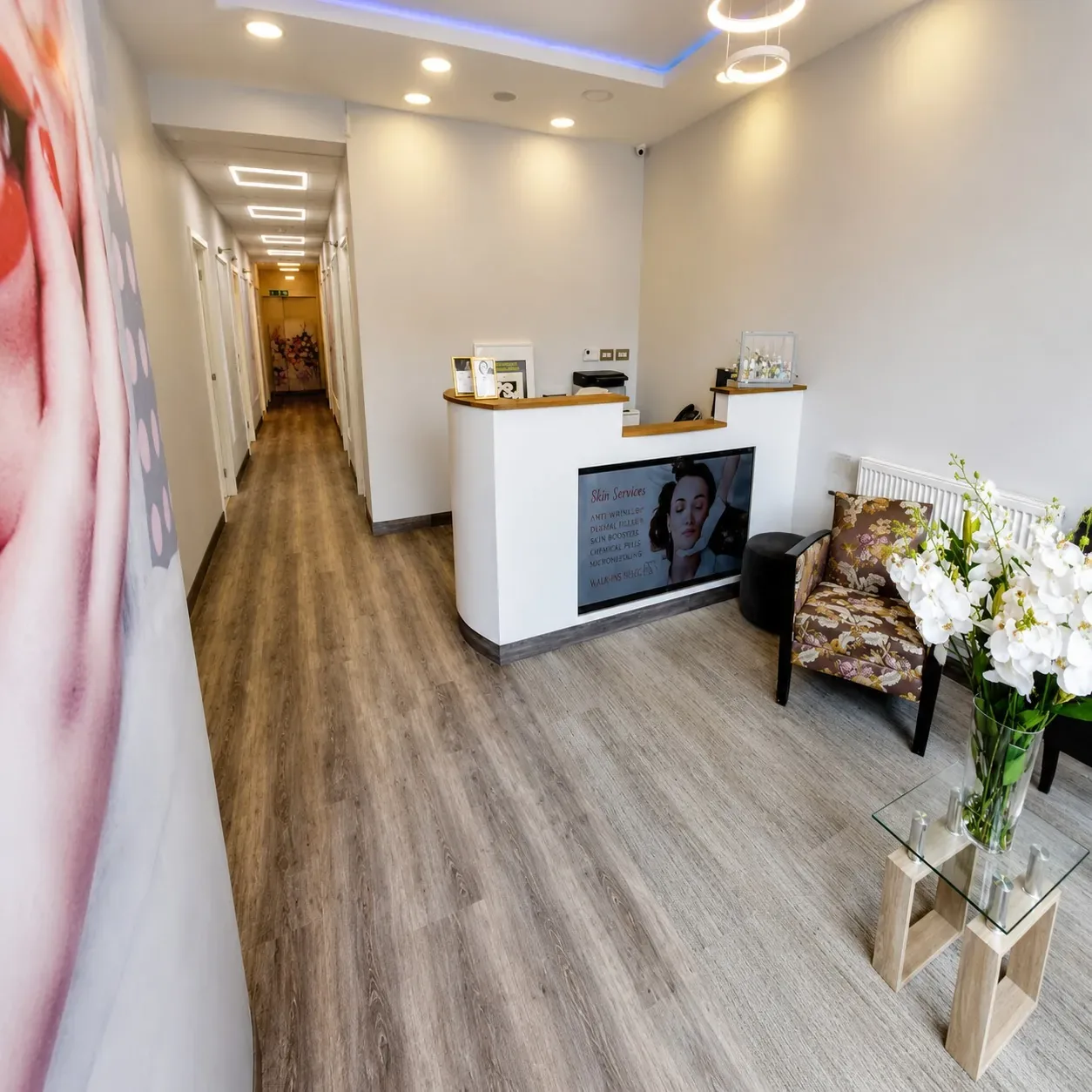 Bright corridor with oak flooring leading to the reception desk and flowers at Stunning Smile Clinic, West Ealing