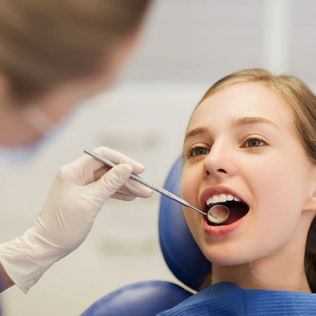 Patient smiling in a dental chair during a check-up with a mirror and probe