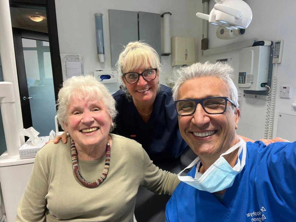 Dr Dariush Hoshyar and a colleague smiling with a patient in the treatment room